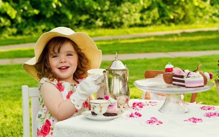 Girl in hat having a tea party with cakes