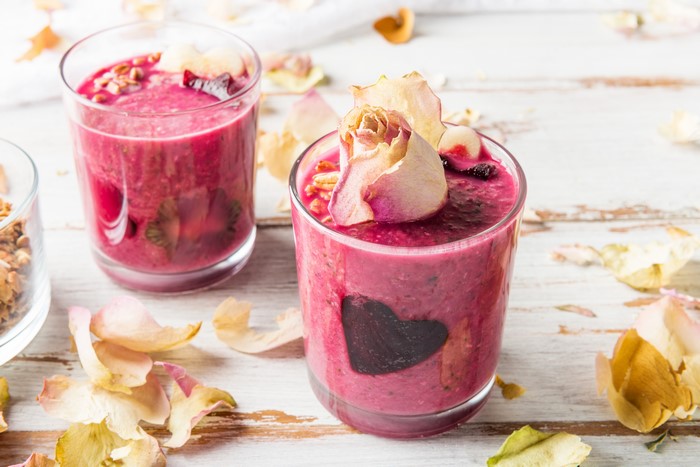 Two smoothies with roses and petals on wood planks