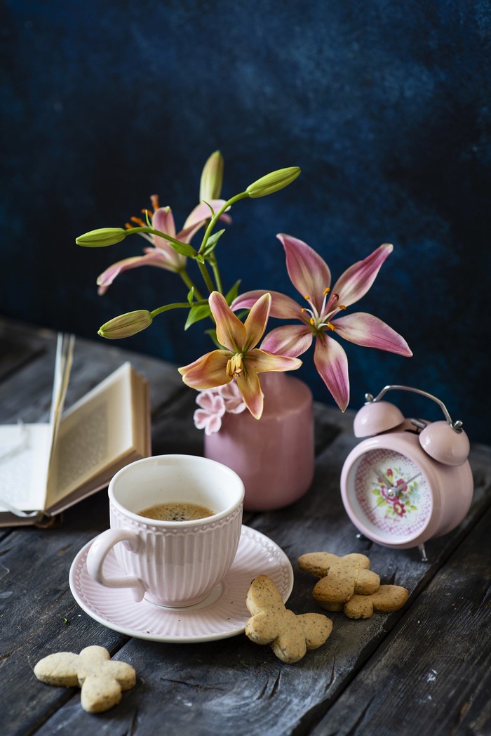 Still life with lilies, coffee, cookies, and alarm clock