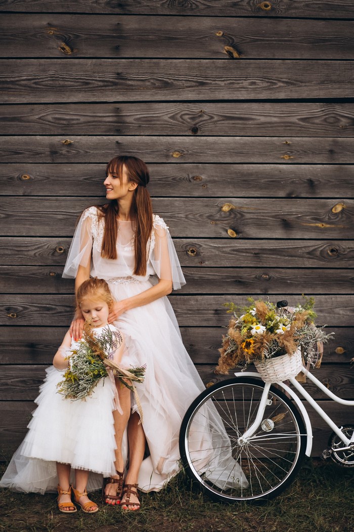 Bride and flower girl with bicycle and bouquets