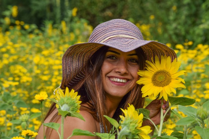 Woman in a hat smiling in a sunflower field