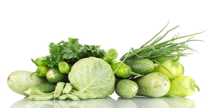 Assortment of fresh green vegetables including cabbage, peppers, cucumbers, zucchini, and scallions
