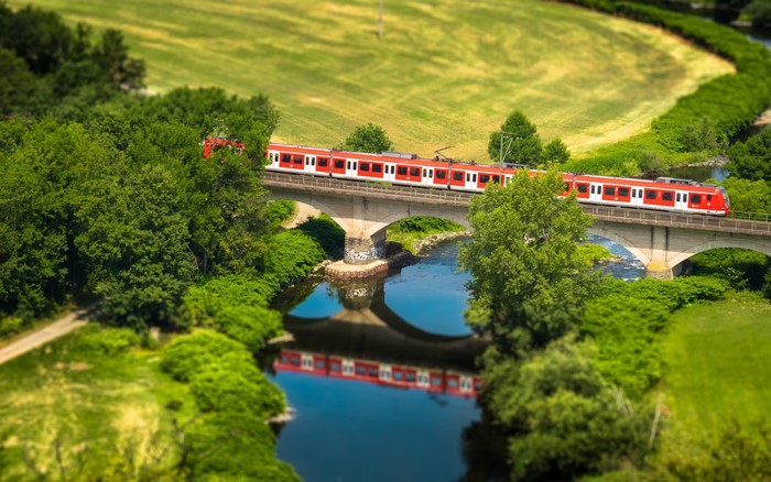Red train crossing a bridge over a river