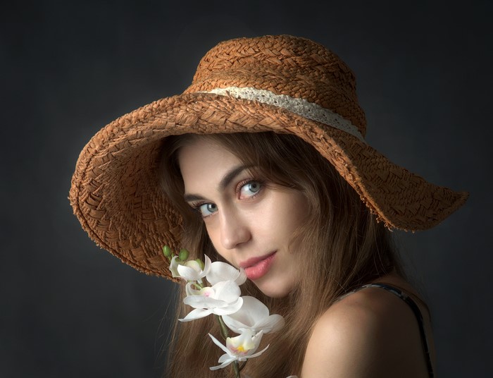 Woman in straw hat with orchid