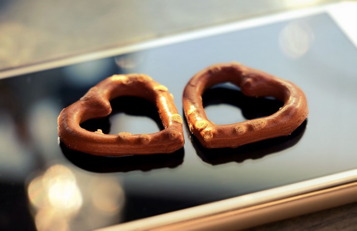 Two heart-shaped chocolate pretzels on a smartphone
