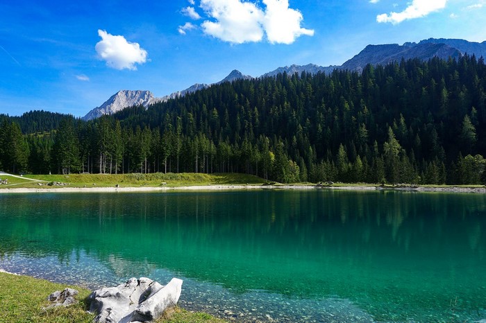 Turquoise lake with pine forest and mountains