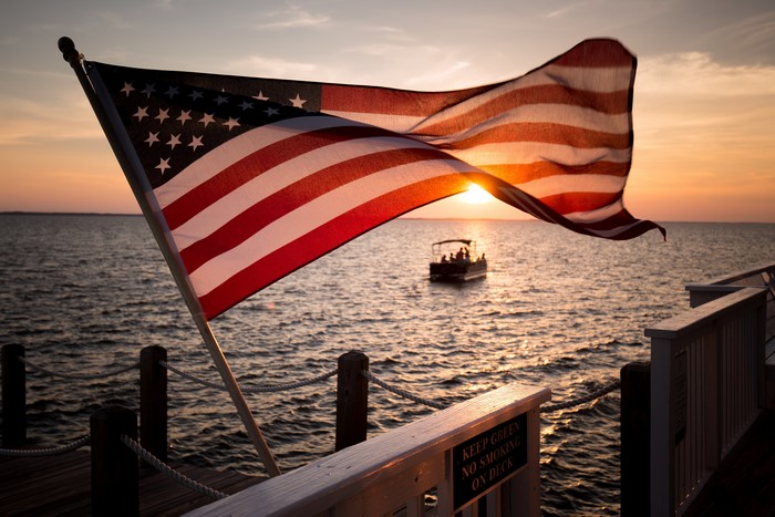 American flag on a dock at sunset with a boat