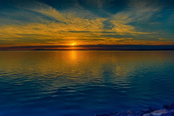 Sunset over a calm body of water with distant land
