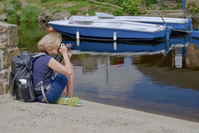 Blonde photographer with backpack by boats