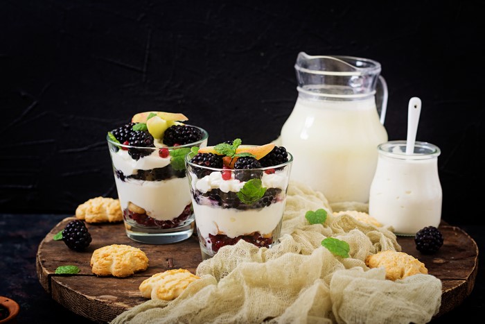 Dessert with blackberries and cream in glasses on a cutting board