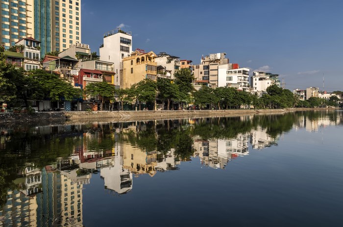 Buildings reflected in a river in Hanoi, Vietnam