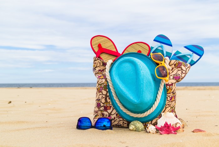 Summer beach accessories: hat, flip-flops, sunglasses, shells, and handbag