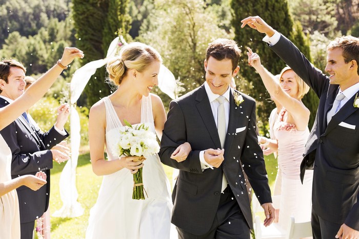 Bride and groom walking with guests throwing confetti