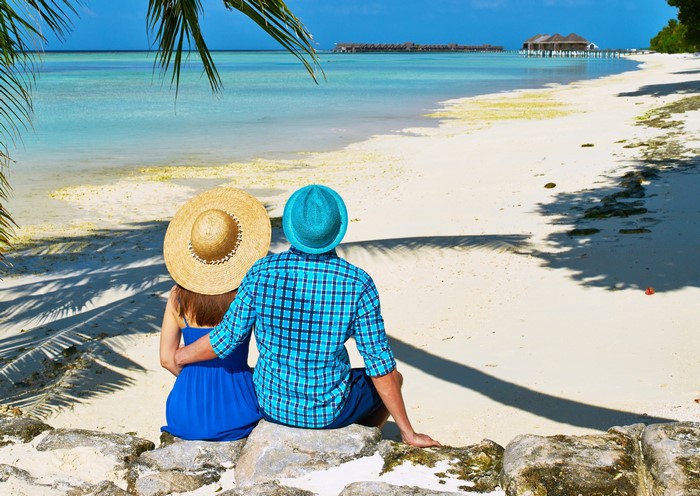Couple sitting on rocks at a tropical beach