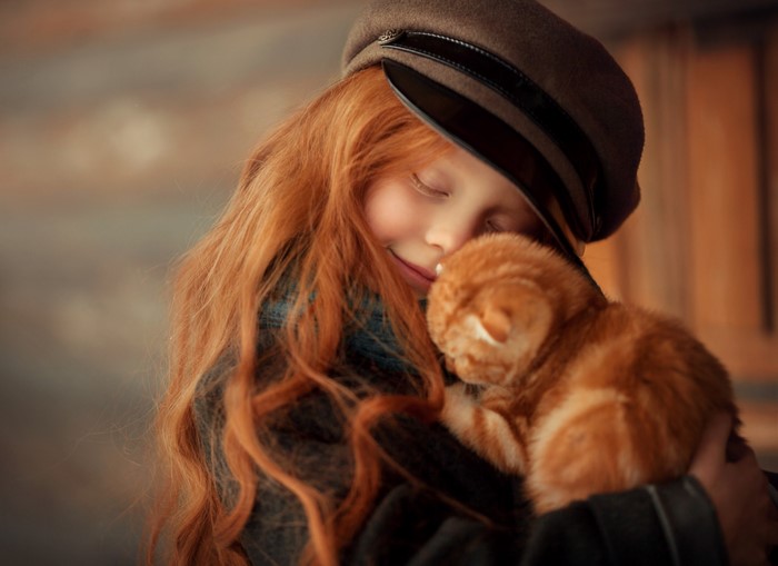 Ginger-haired girl hugging an orange cat