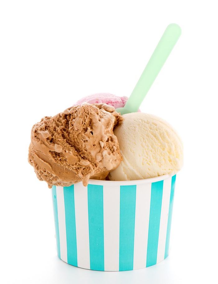 Ice cream scoops in a striped cup with a spoon