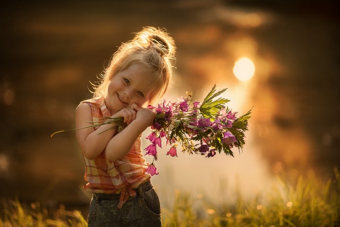 Little girl holding a bouquet of flowers at sunset