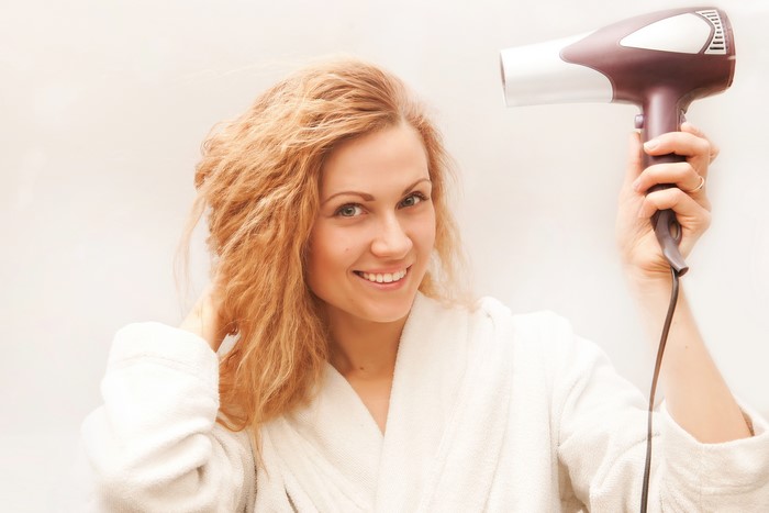 Blonde girl with hair dryer smiling