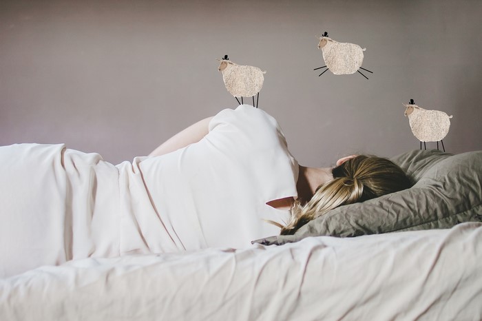 Person sleeping with sheep jumping over them