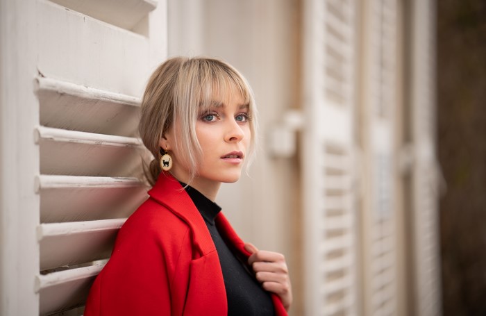 Blonde girl with bangs wearing red jacket and cat earrings