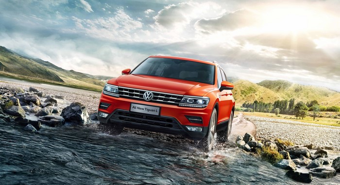 Orange Volkswagen Tiguan L driving through water