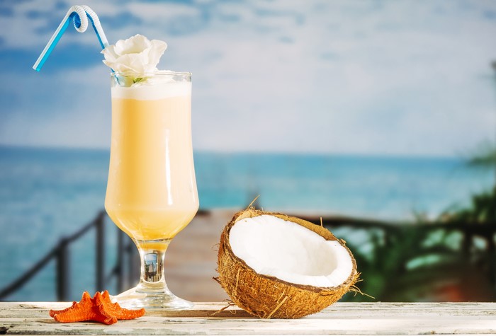 Pina Colada cocktail with coconut and starfish on beach