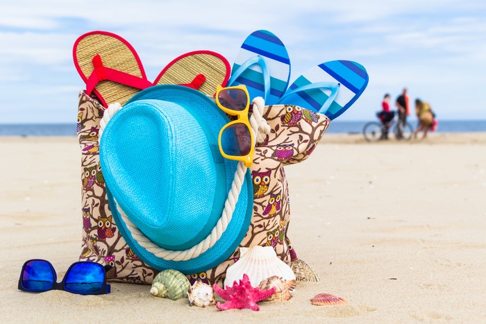 Summer beach bag with hat, flip-flops, and sunglasses