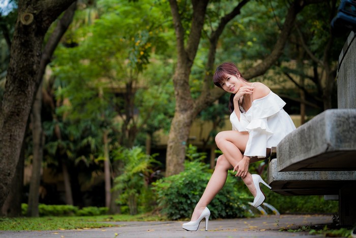 Asian woman with brown hair sitting on a park bench