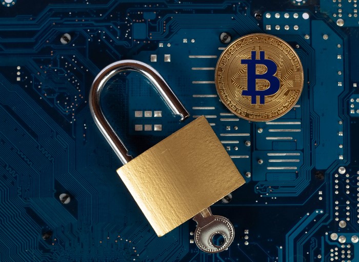 Bitcoin coin with padlock and key on circuit board