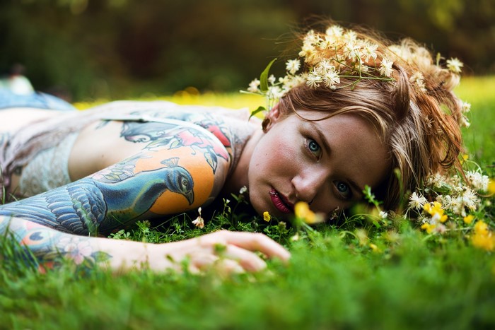 Woman with peacock tattoo lying in grass