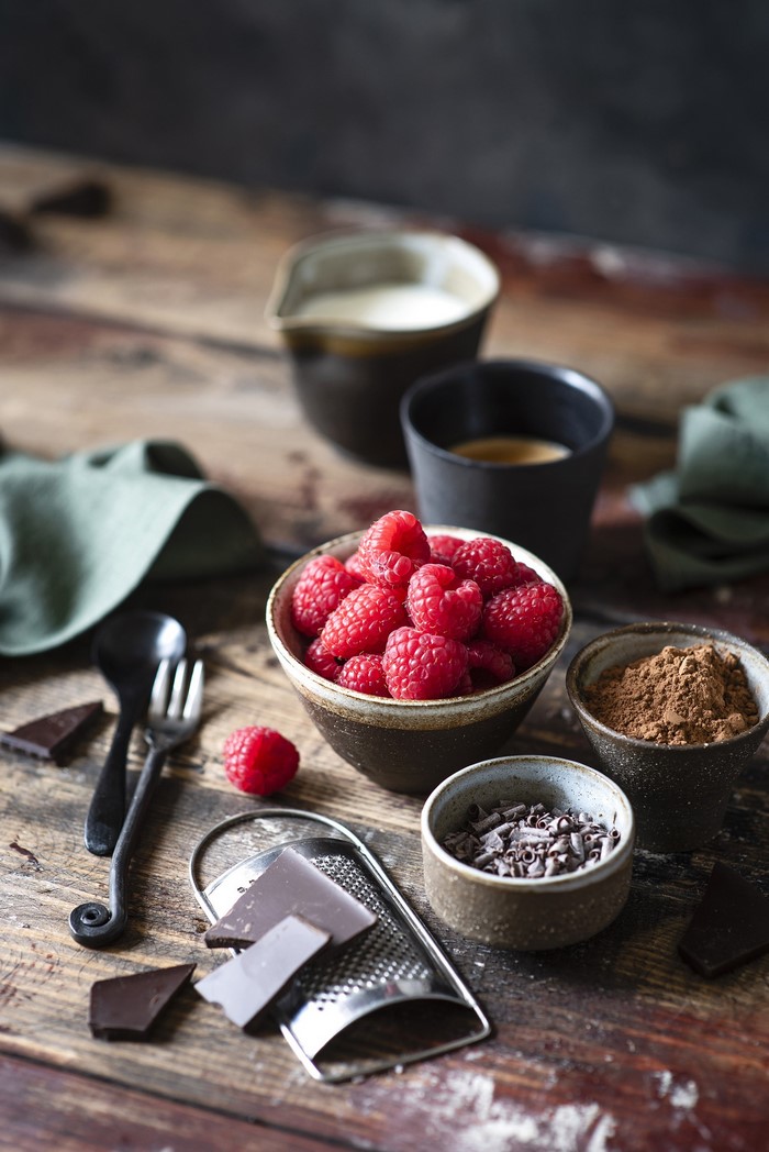 Raspberries, chocolate, and cocoa powder on wooden table