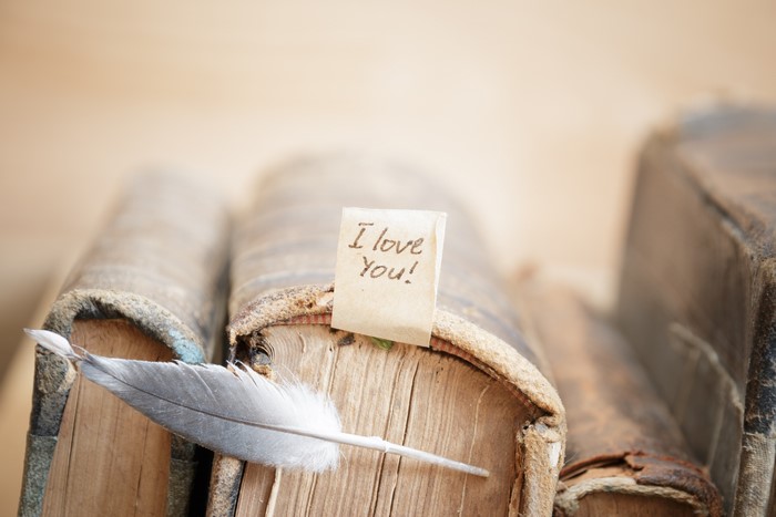 I Love You note on old books with feather