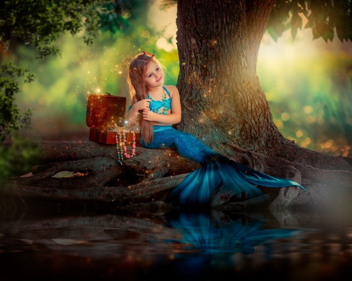 Mermaid girl with treasure chest by a tree
