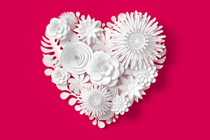White paper flowers in a heart shape on a red background