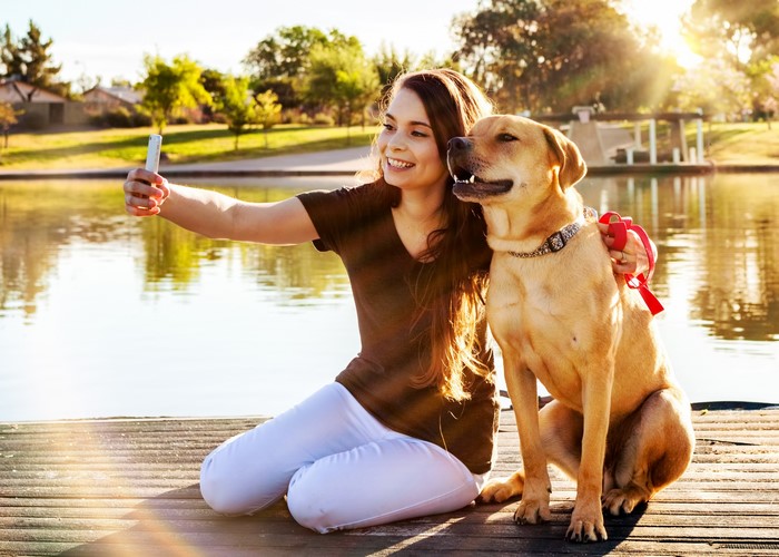 Girl taking a selfie with her dog by a lake