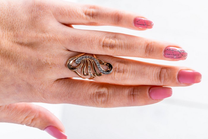 Hand with pink manicure and gold ring