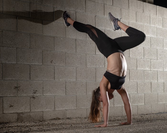 Woman doing a handstand against a brick wall
