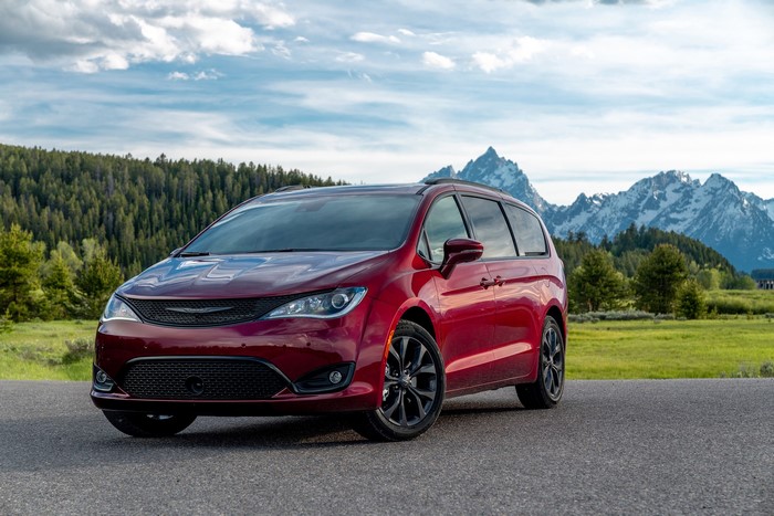 Red Chrysler Pacifica minivan parked on a road with mountains