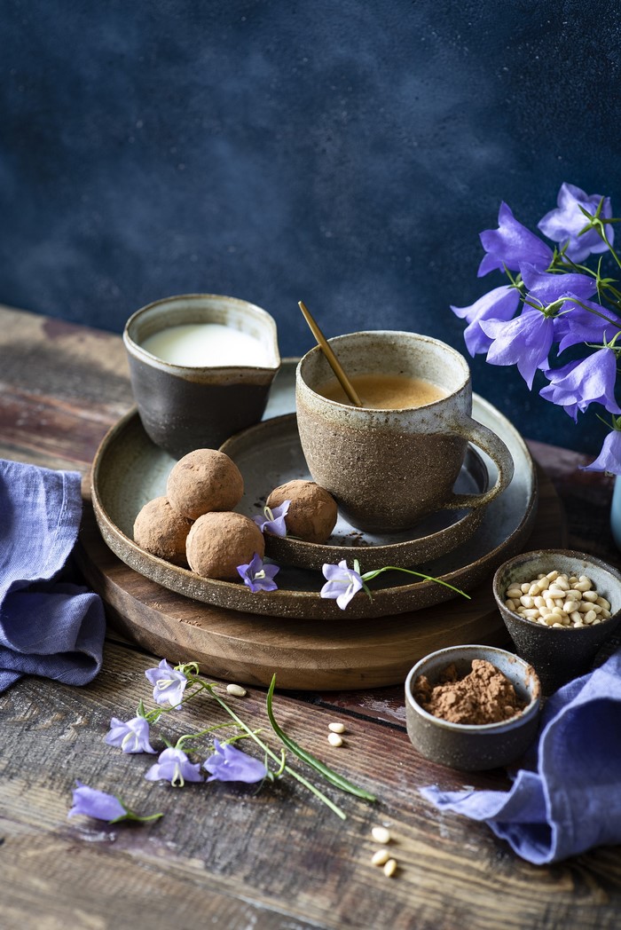 Coffee, truffles, milk, and flowers on a wooden table