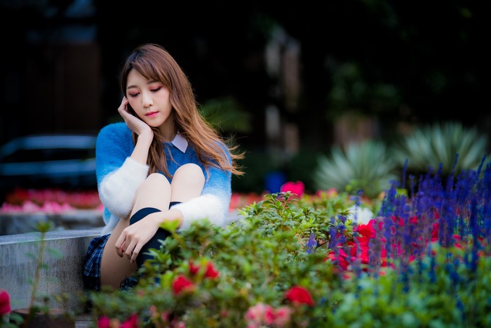 Cute Asian girl with brown hair sitting in park