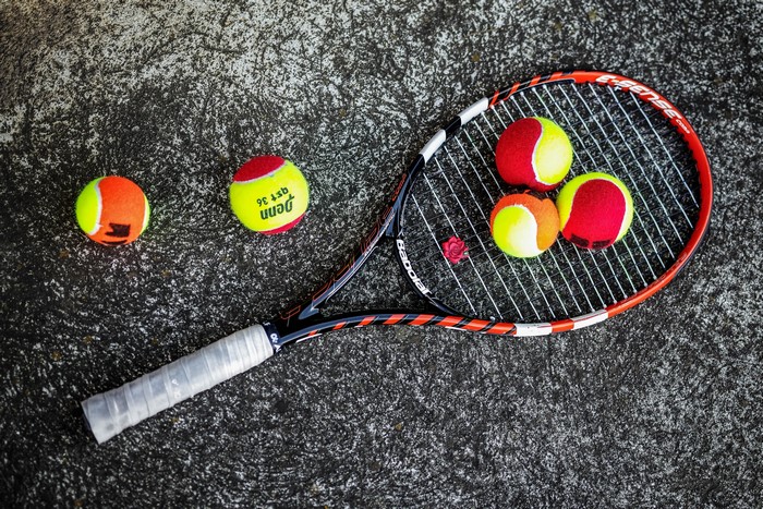 Tennis racket and balls on a textured surface