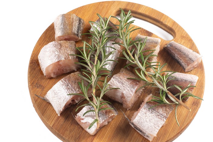 Fish pieces with rosemary on a cutting board