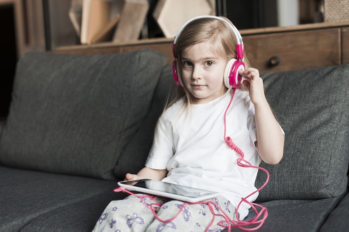 Girl with headphones and tablet on couch