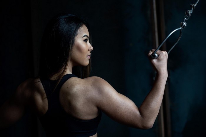 Gladysha Asian fitness model doing cable pull-downs