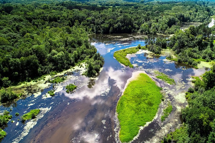 Aerial view of a river winding through a dense forest in Kost, Minnesota.