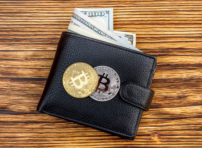 Black leather wallet with Bitcoin coins and US dollars