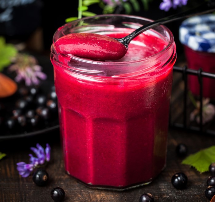 Blackcurrant jam in a jar with a spoon