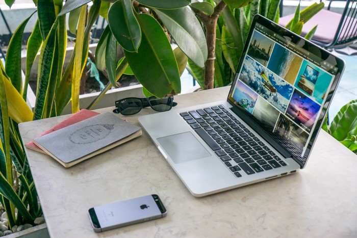 Laptop, smartphone, notebooks, and sunglasses on a table