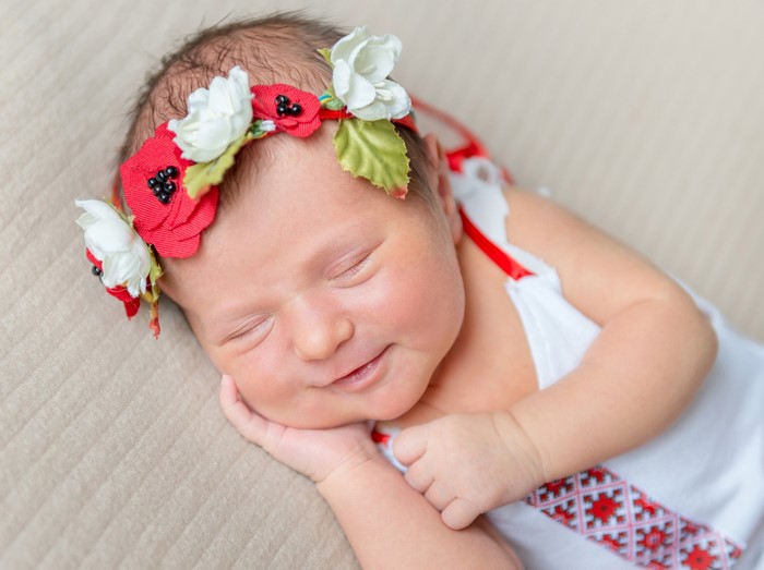 Newborn baby wearing a floral wreath and traditional clothing