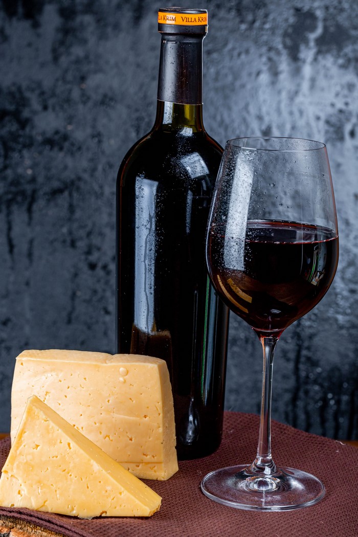 Bottle of Villa Krim wine with cheese and a glass